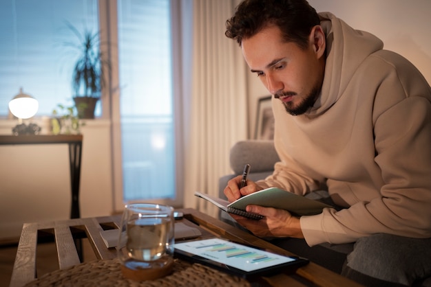 A person sitting at a table reviewing bills with a tablet displaying budgeting software, highlighting the importance of tracking expenses and managing finances during unemployment.