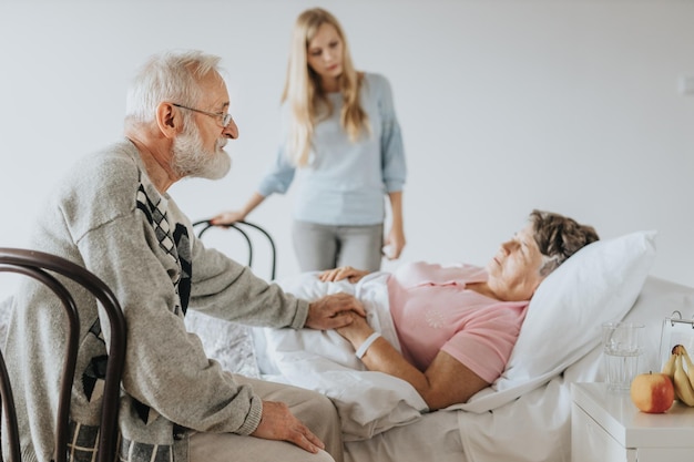 An elderly person in a hospital bed, surrounded by family members, with a doctor explaining something. The image conveys the importance of healthcare directives and having a plan in place for medical decisions.