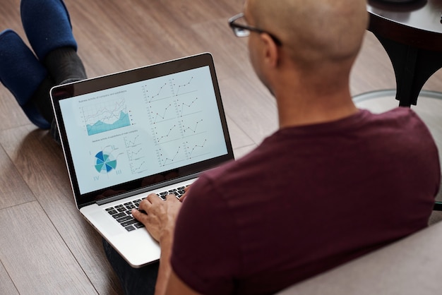 A person sitting at a desk, working on a laptop, with financial charts and graphs displayed on the screen. The person appears focused and is using a calculator, conveying the importance of careful financial planning.