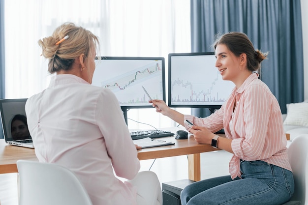 A financial advisor shows investment growth charts, explaining financial strategies to a client while sitting in front of a computer.