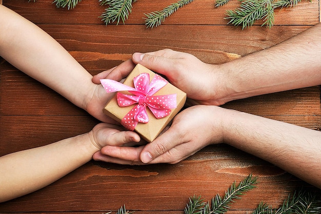 A hand symbolically giving a gift, with a family smiling in the background, representing the act of gifting and its positive impact on future generations. The image should convey generosity and familial love.