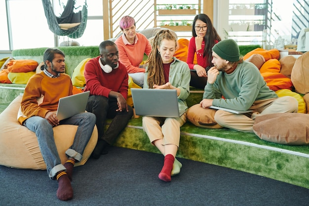 A diverse group of students sitting in a modern library, studying and collaborating on laptops and books. The ambiance is bright and conducive to learning, symbolizing the opportunities that student loan forgiveness can provide for academic and professional advancement.