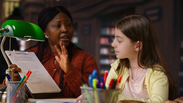A special education teacher working one-on-one with a student on a reading exercise. The teacher is using visual aids and positive reinforcement.