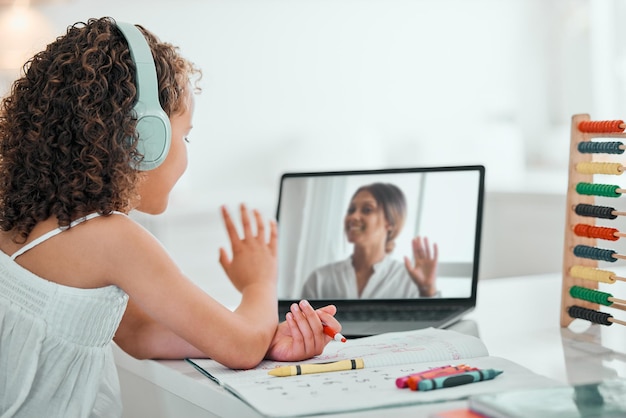A child happily participating in an online class from their home, interacting with a teacher and classmates through a video call.