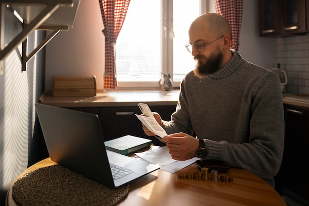 A person sitting at a desk, reviewing a budget spreadsheet on their laptop, with bills and financial papers organized neatly on the desk. The scene should convey careful financial planning.