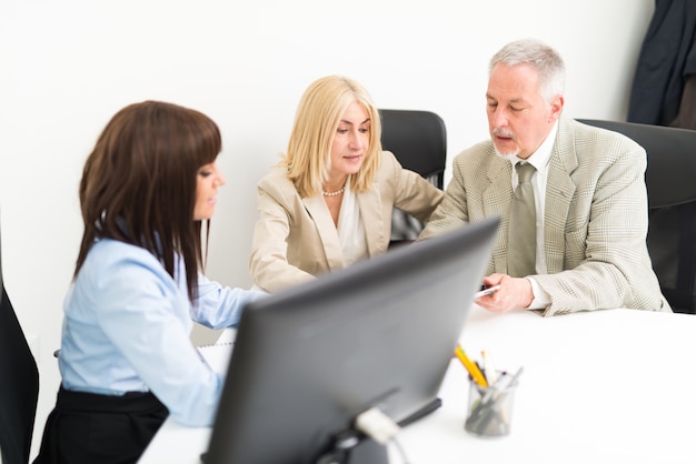 A friendly insurance agent sitting across from a client at a bright, modern office desk, reviewing documents with a pen in hand. The scene suggests trust and transparent communication.