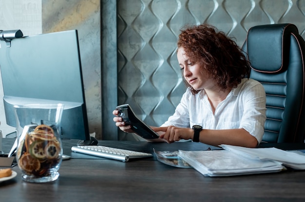 A person using a budgeting app on their phone while sitting at a desk, showing how technology can aid in managing finances and setting financial goals.