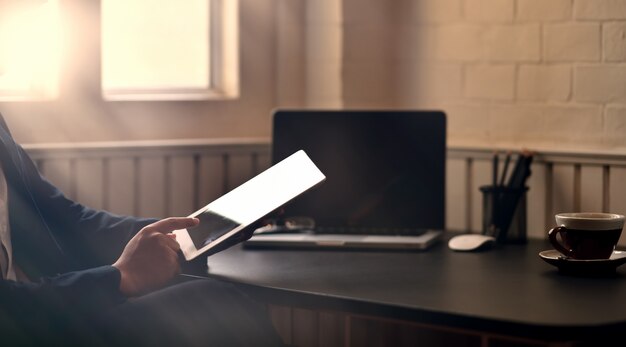 A person using a tablet to access AnnualCreditReport.com, showcasing the website interface on the screen. The background shows a comfortable home office setting.