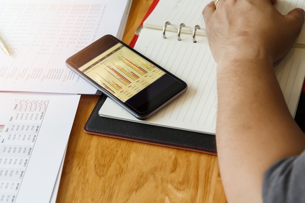 A person using a mobile budgeting app to track their daily expenses, with graphs showing potential savings and investment growth.