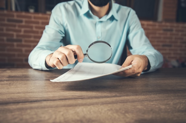 A close-up of a person's hands holding an SPD document, with a magnifying glass resting on the page. The focus is on the detailed text and fine print of the document, emphasizing the need for careful review and understanding.