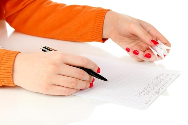 A close-up of a hand filling out a student loan forgiveness application form. A pen is poised above the signature line. The setting is a clean, modern office space. The image emphasizes the process of applying for student loan forgiveness.