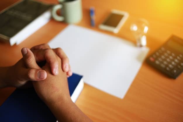 A close-up shot of a person filling out a student loan forgiveness application form, with a pen in hand and a calculator and various financial documents around the table.